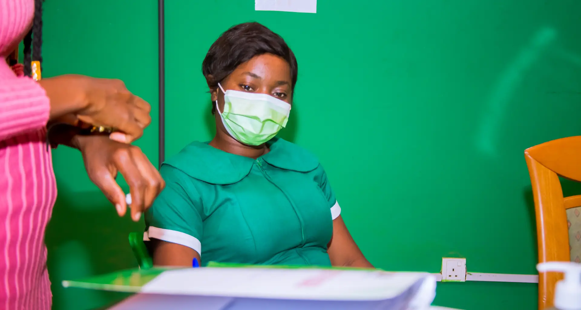 A MAON nurse in a green uniform at her desk.